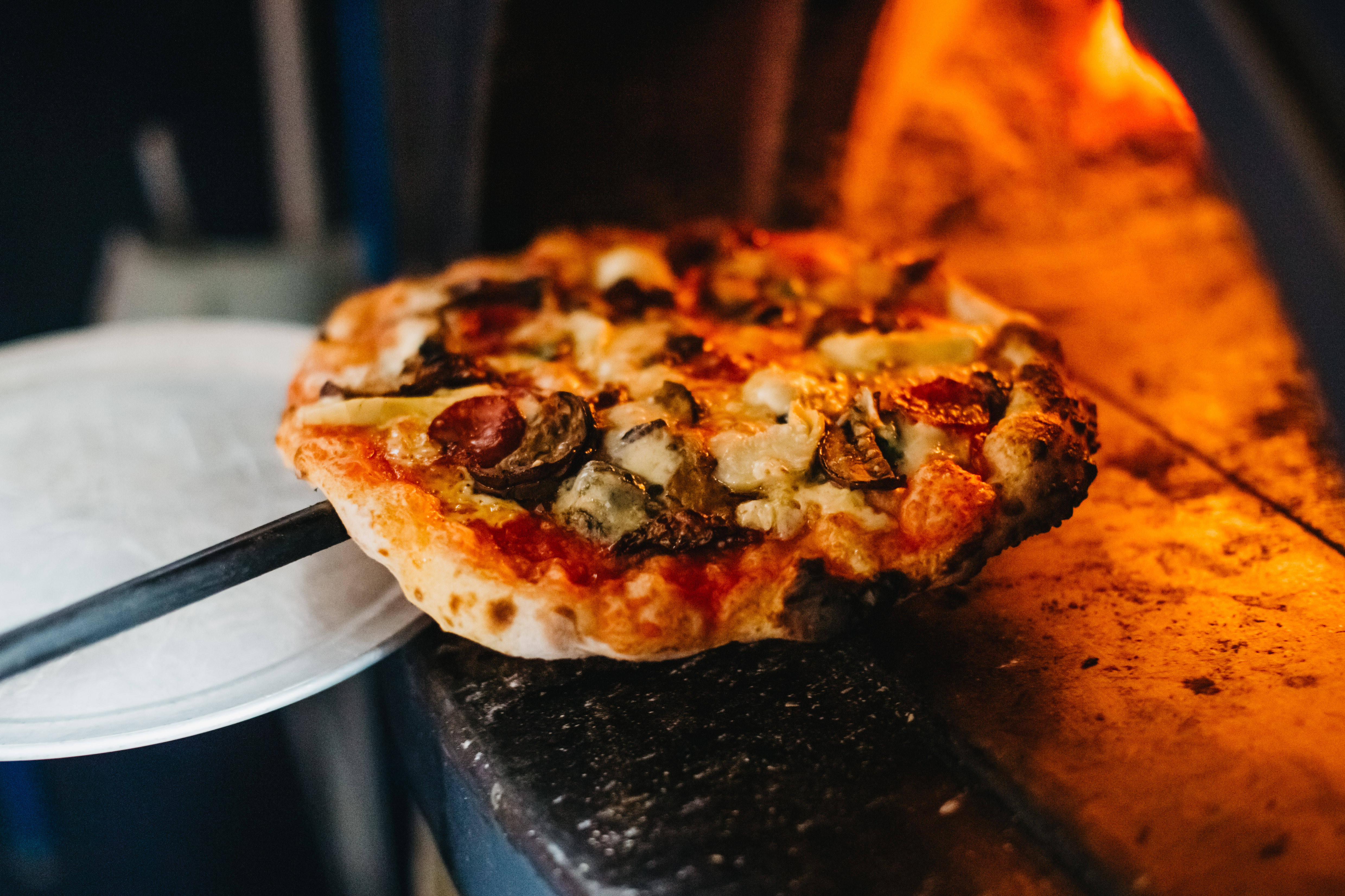 A pizza on a peel being removed from a wood fired oven